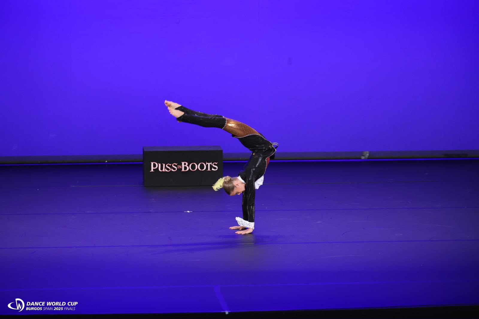 Moondance acro dancer in a controlled handstand on stage